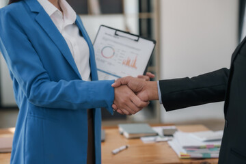Businesswoman shakes hands with a man in a suit.