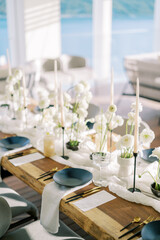 Black plates on white napkins stand next to gold cutlery and menus on a holiday table with white flowers