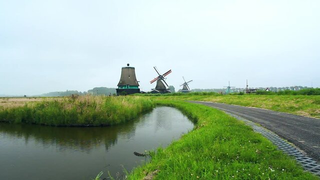 Paisaje panor&aacute;mico Holand&eacute;s de molinos de viento centenarios en funcionamiento con canales y camino circundante