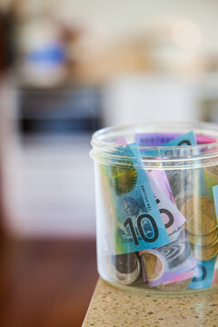 Australian money notes and coins in jar on counter