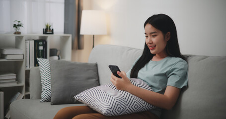 Selective focus ,Happy young woman sitting on sofa enjoy using mobile phone for online shopping cashless in living room at home