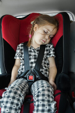 Four year old child strapped into her car seat sleeping on a long road trip