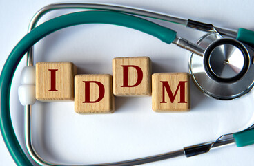 Cubes with the abbreviation IDDM on the background of a stethoscope.