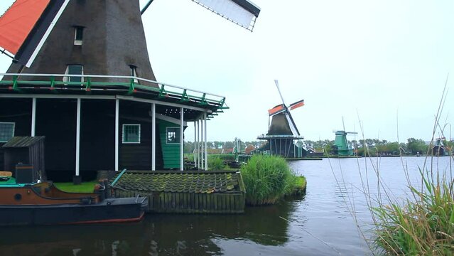 Movimiento de c&aacute;mara de molinos de viento holandeses hist&oacute;ricos en funcionamiento a r&iacute;o en Zaanza Schans 