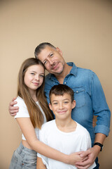 proud father with his son and his daughter posing in front of brown background