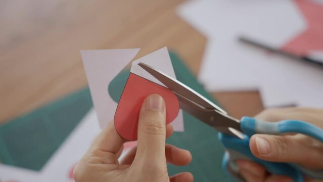 Cutting red Paper for Valentine Card on green background. Valentine's Day, February 14th. Love, emotions, feelings. First love for Valentine's Day. close up video stock