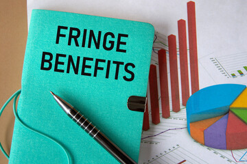 FRINGE BENEFITS - words on a green piece of paper on the background of a chart and a pen