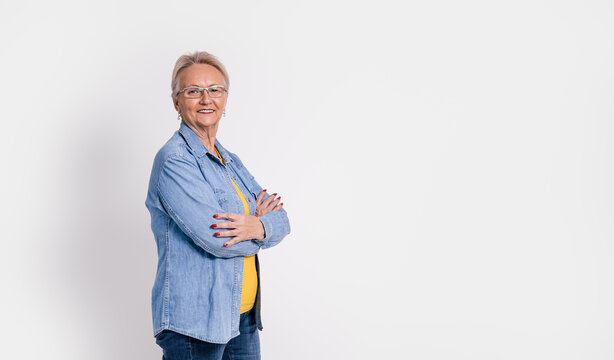 Portrait of old confident businesswoman with arms crossed smiling and standing on white background