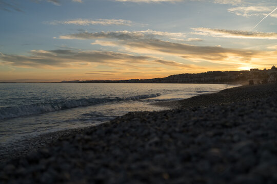 Sunset on the French Riviera pebble beach in Nice with blurred people walking on the beach