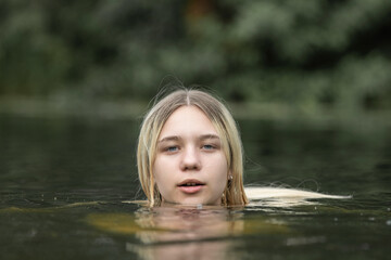 Portrait of a young beautiful blonde girl by the river.