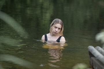 Portrait of a young beautiful blonde girl by the river.