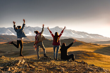 Four happy tourists without backpacks are enjoying sunset in mountains