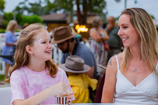 Tween girl eating snow cone and chatting with parent while out together