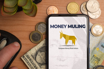 Money muling and European Money Mule Actions concept: smartphone on a table sorrounded by money