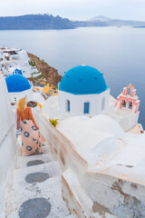 woman model is walking strrets of Oia town on Santorini island in Greece. Travel mediterranean aegean of traditional cycladic Santorini white houses and blue dome