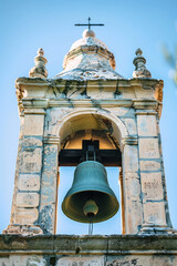 Obraz premium Bell Tower Against Blue Sky background with copy space. Orthodox bell tower of a traditional church with cross on top. Bell ringing, the work of the bell ringer.