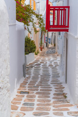 narrow side street with traditional whitewashed walls and blue accents in Mykanos Greece. traditional windmill on the sea shore and colorful restaurants