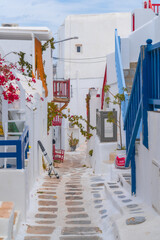 narrow side street with traditional whitewashed walls and blue accents in Mykanos Greece....