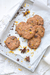 home made chocolate cookies with orange zest, chocolate chips and spices perfect for christmas on grey wooden background close up selective focus