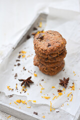 home made chocolate cookies with orange zest, chocolate chips and spices perfect for christmas on grey wooden background close up selective focus
