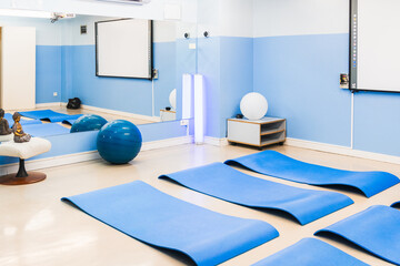 A tranquil yoga room with blue mats, exercise balls, and ambient lighting.
