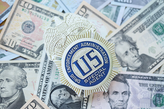 KYIV, UKRAINE - MARCH 9, 2024 US DEA Special Agent badge on many US dollar bills close up