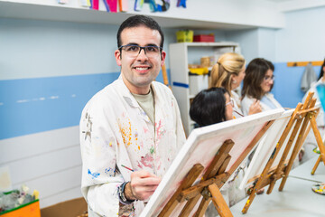 Concentrated man with glasses painting in a disability-friendly art class."