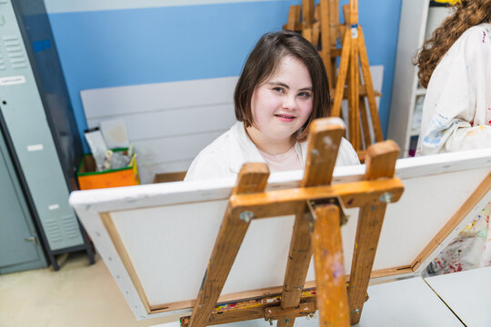Focused woman with Down syndrome painting in an art workshop.