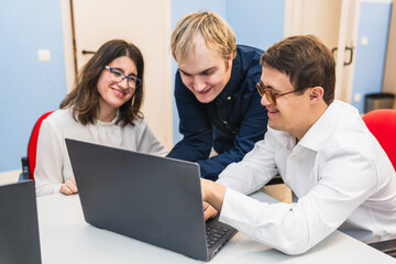 Students with disabilities and one with Down syndrome work together on a computer project.