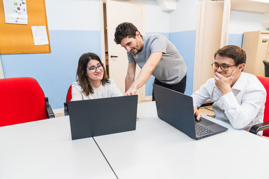 Teacher smiles at student with Down syndrome during computer class.
