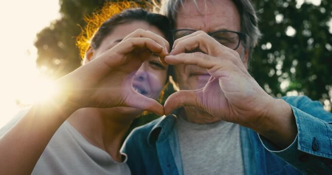 Father and daughter making a heart shape with their hands	