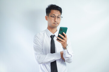 Young businessman in eyeglasses reading news over mobile phone against white background