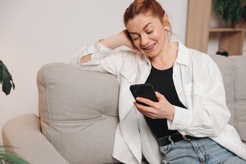 Portrait of mature smiling woman with braces using smart phone at home