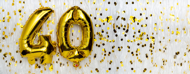 Golden foil balloon number, figure forty on white with confetti background. 40th birthday card....