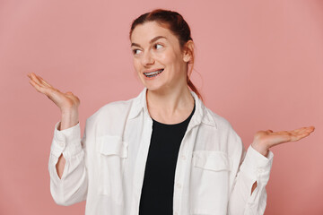 Modern happy woman showing smile with braces on pink background