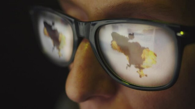 Cg footage. The glasses on the female face reflect a search for information on the Internet and a map of Ukraine with explosions and fire