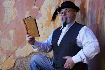 Man with beard pipe hat and vintage clothes reading a book