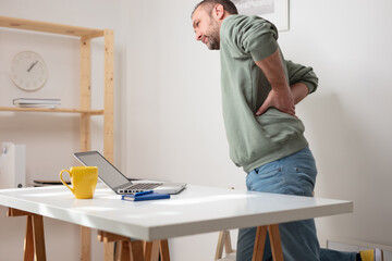 Man with back pain while working on a laptop.