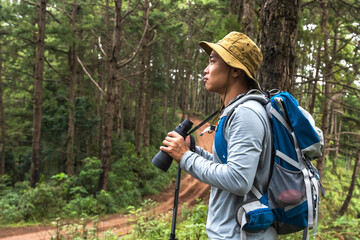 Portrait Asian birdwatcher using binocular searching for birdwatching in forest