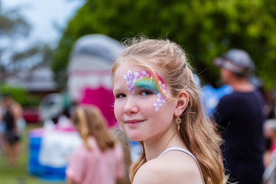 Girl in face paint waiting in line for the slip and slide at summertime event