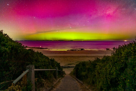 Aurora Australia illuminating the night sky over a staircase leading down to a beach
