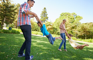 Parents, children and spinning fun in garden for bonding game together on park field for summer,...
