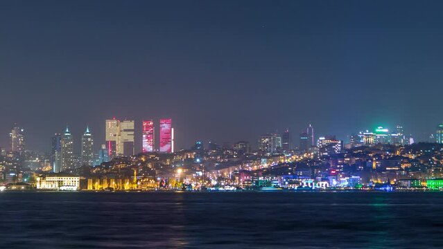 Night timelapse view of besiktas district with some illuminated skyscrapers in Istanbul taken from asian part of the city. Reflection on Bosphorus water