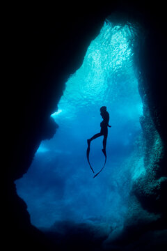 silhouette of free diver woman freediving in cave.