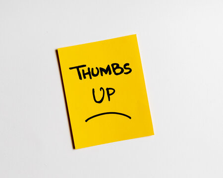 Yellow sticky note with text "thumbs up". with happy smiley face