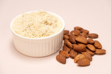 Almond flour and almonds on a beige background
