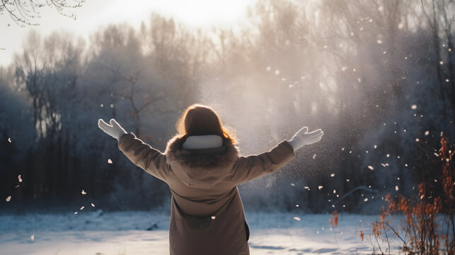 Young girl throwing snow in the air at sunny winter day