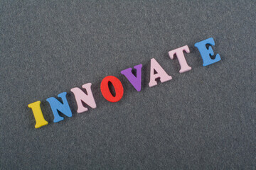 INNOVATE word on black board background composed from colorful abc alphabet block wooden letters, copy space for ad text. Learning english concept.