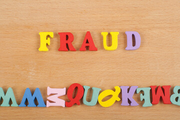 FRAUD word on wooden background composed from colorful abc alphabet block wooden letters, copy space for ad text. Learning english concept.