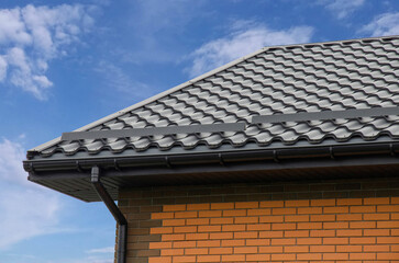 Metal roof tile with plastic gutter system